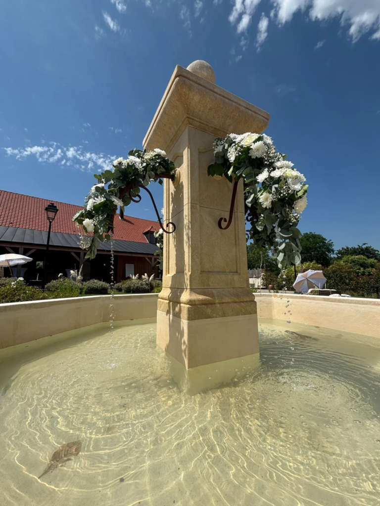 La fontaine ornée de fleurs et sous le soleil
